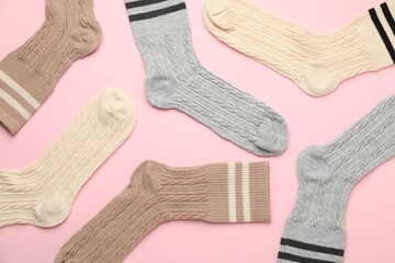 Different comfortable socks on light pink background, flat lay