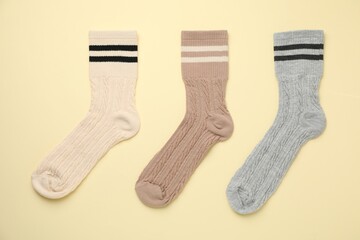 Different comfortable socks on beige background, flat lay