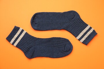 Pair of soft comfortable socks on orange background, top view