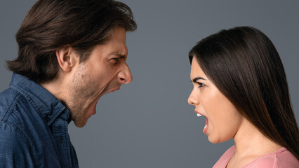 Relationship Crisis. Angry Young Couple Screaming At Each Other Over Light Studio Background, Side View