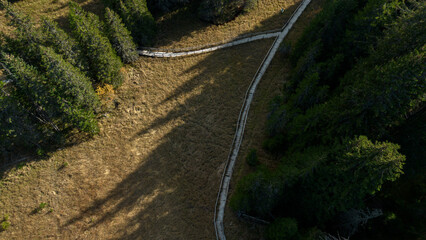 A picturesque wooden walking path through Jankove Bare swamp in autumn season. Quiet Nature Trail, beautiful landscape. Aerial view of a wooden path over a swamp in Kopaonik National Park in Serbia.