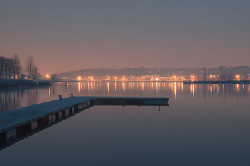 Fototapeta premium Tranquil Waters at Night with Distant City Lights Reflecting on Serene Lake Surface
