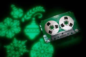 Christmas music theme background. Green light projections of christmas tree toys on a dark background and an audio cassette
