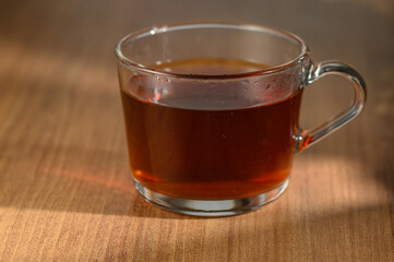 Warm cup of aromatic herbal tea resting on a wooden table in soft morning sunlight