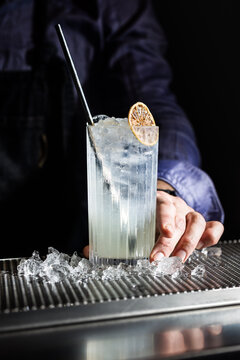 Refreshing tall gin fizz cocktail with ice and garnish on bar counter