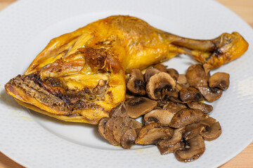 oven roasted chicken thigh with sliced mushrooms on a white plate on a wooden table