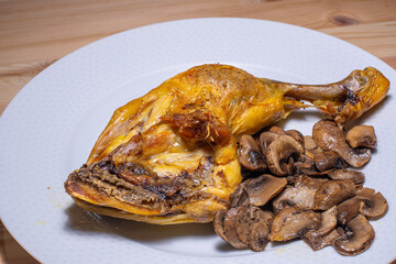 oven roasted chicken thigh with sliced mushrooms on a white plate on a wooden table