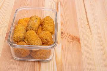 Chicken mushroom and cod croquettes arranged in a glass container on a wooden table