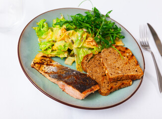 Baked salmon steak with crispy toasts and fragrant Mediterranean salad of lettuce with walnuts, pumpkin seeds and mustard vinaigrette