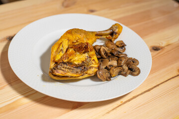 oven roasted chicken thigh with sliced mushrooms on a white plate on a wooden table