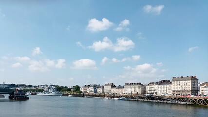Picturesque riverside city with historic buildings against blue sky with fluffy clouds