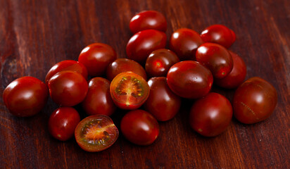 Ripe red cultivated species kumato tomatoes on wooden background. Healthy vitamin product