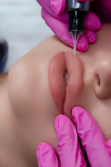 A beautician does permanent lip makeup on a woman. Tattooing in a beauty salon.