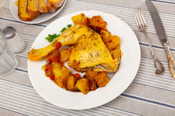 plate of fried chicken leg and vegetable stew of potatoes and carrots sits on table covered with checkered tablecloth.selective focus