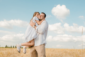 Dad with his daughter in his arms against the background of nature. They play together, laugh, hug and kiss