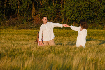  Family holiday. Child mom dad walking holding hands. Happy family of farmers raising their hands outdoors at sunset. Teamwork of group of people walk in wheat field. Child parents.