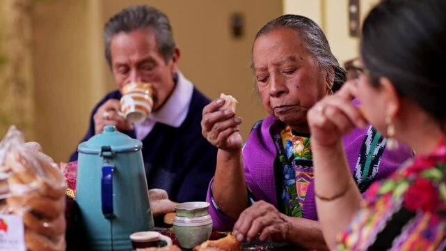 Close-up of a Latin family chatting during a snack, they enjoy hot chocolate and sweet bread.