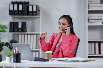 business asian woman with talking on mobile phone and work on documents and laptops for. Confident business woman working in the office workplace,