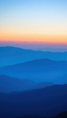 Fototapeta premium mountains are silhouetted against a blue and orange sky at sunset