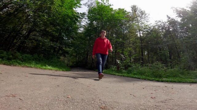 Woman walking in a forest struggles with dizziness and balance issues. The camera captures her efforts to remain upright amid the surrounding trees and sunlight