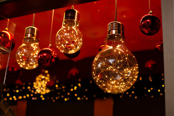 Above view on pine tree branches with Christmas fairy lights and red baubles.