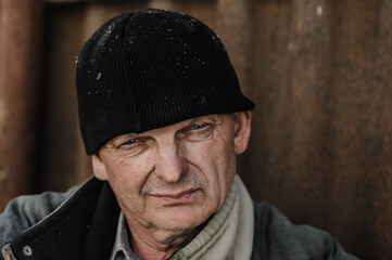 A portrait of a hardworking pensioner is carried. The face of an elderly man. Portrait of an old man in a black hat.