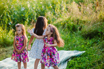 Happiness, sisters children having fun together in a green garden  In Ukraine.Smiling children are playing with bubbles in the park.