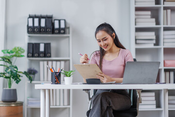 Asian Businesswoman Using laptop computer and working at office with calculator document on desk, doing planning analyzing the financial report, business plan investment, finance analysis concept.
