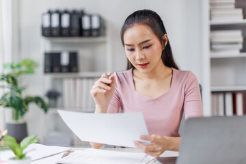 Asian Businesswoman Using laptop computer and working at office with calculator document on desk, doing planning analyzing the financial report, business plan investment, finance analysis concept.
