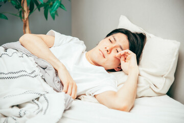 寝室でだるそうな男性
