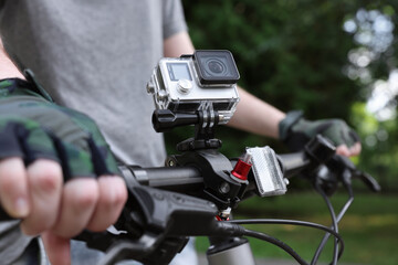 Man riding bicycle with modern action camera outdoors, closeup