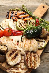 Delicious grilled vegetables and chicken breast on wooden table, closeup