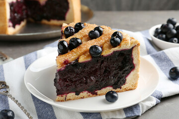 Slice of delicious homemade blueberry pie served on grey table, closeup