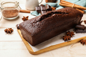Tasty chocolate sponge cake and ingredients on white wooden table, closeup
