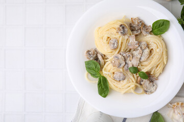 Delicious pasta with mushrooms and basil on white tiled table, top view. Space for text