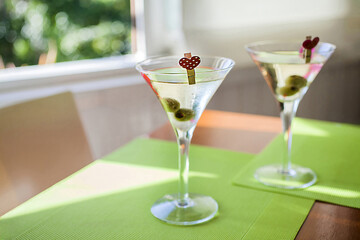 Two martini cocktails celebrating valentine's day with green olives and heart decorations