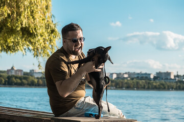 A small black dog is playing with a boy.puppy laying flat on the green grass resting