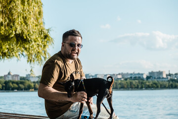 A man is playing with a dog in the park.Cute little dog in the hands of a guy.Adorable, funny...