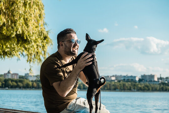 Active little black dog.A man in a white shirt hugs his dog.