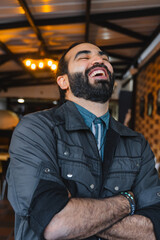 Latin man with beard and long hair smiling on restaurant terrace. Happy and smiling people. Smile day.