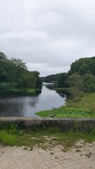 Paisagem com muro de pedras, rio em perspectiva, e árvores verdes.