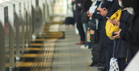 朝の通勤時間の駅のホームで電車待ちの人々の姿