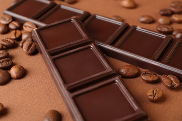 Pieces of tasty chocolate and coffee beans on brown background, closeup