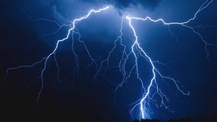 Dramatic night sky with intense electric blue lightning bolts during storm
