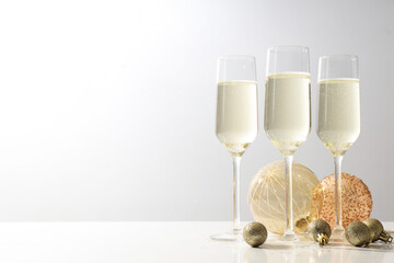 Glasses of champagne with Christmas balls on a light background