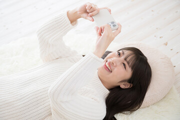 仰向けで寝転がりスマホを見る若い女性　俯瞰