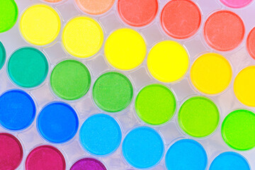 Colorful paint palette of watercolors, arranged in rainbow of colors, is an essential tool for artists hobbyists.