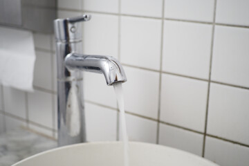 Fresh water is flowing gracefully from a sleek, shiny chrome faucet in a cozy kitchen setting,