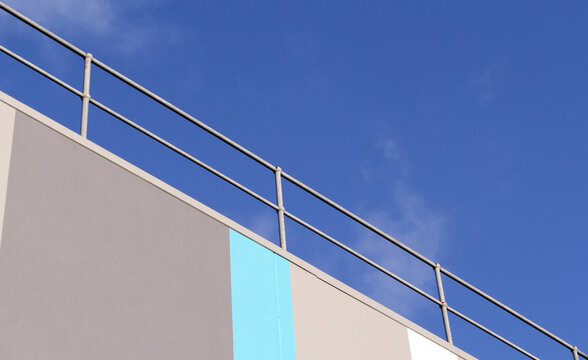 Building roof with a railing against a bright blue sky background