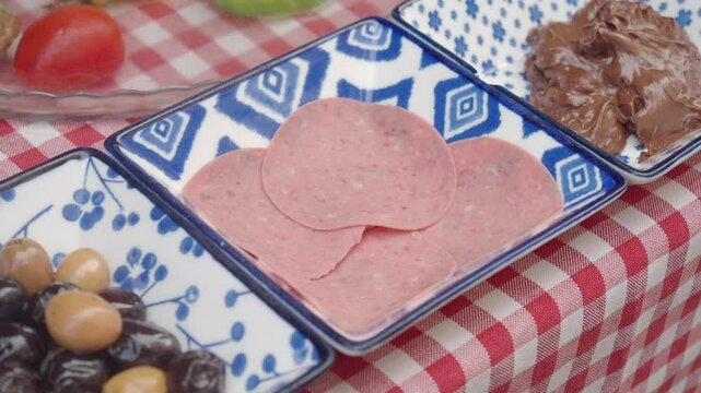 An inviting display of sliced deli meat and a chocolate spread on patterned plates.
